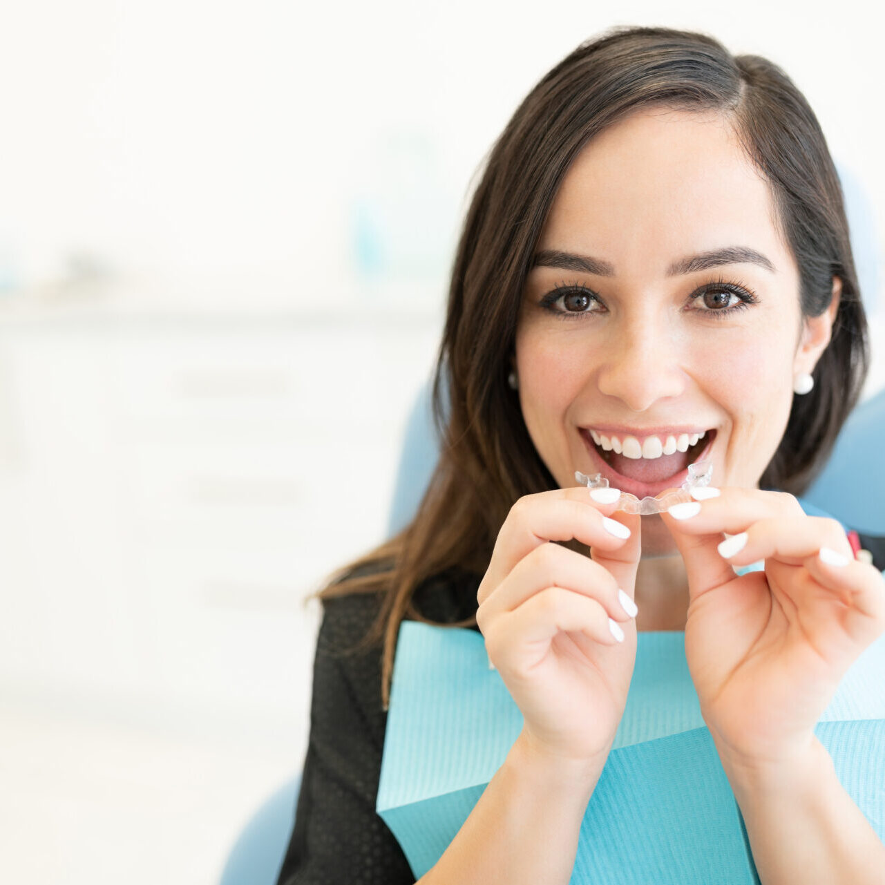 Happy mid adult woman with clear orthodontic retainer in dental clinic