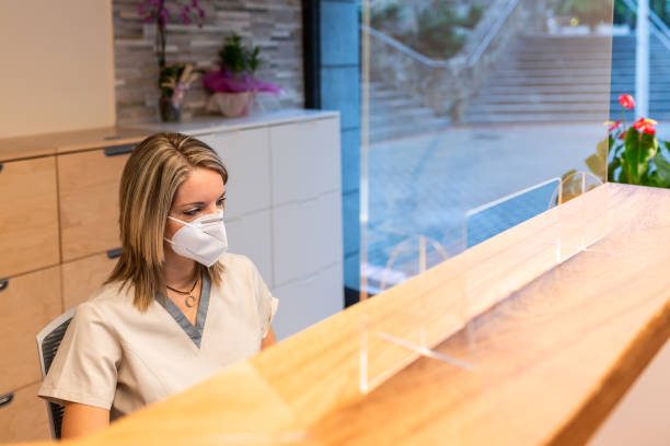 Dentist Reception female receptionist from a dentist center behind a reception desk with a translucent screen.